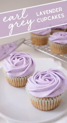 two cupcakes with purple frosting sitting on a plate next to a cooling rack