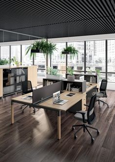 an office with wooden floors and desks in the middle, along with large windows