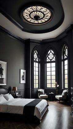 a large bedroom with black walls and wooden flooring, along with two arched windows