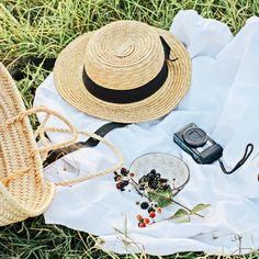 a hat, cell phone and other items are laid out on the ground in the grass