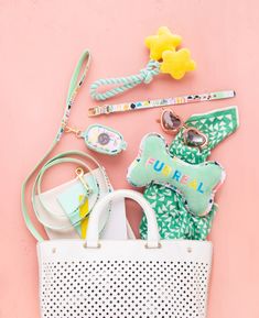 a white purse sitting on top of a pink wall next to other items and accessories