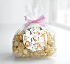 a clear bag filled with popcorn and topped with a pink ribbon that says ready to pop