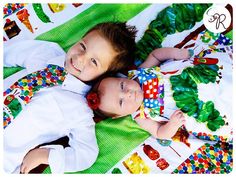 two young children laying on top of each other wearing colorful clothing and ties, smiling at the camera