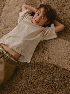 a young boy laying on top of a brown carpet