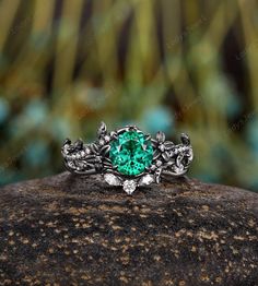 a green ring sitting on top of a rock with leaves and vines around the band