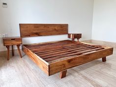 a wooden bed frame sitting on top of a hard wood floor next to two nightstands