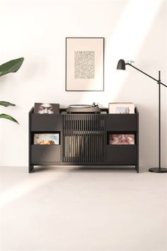 a black record player sitting on top of a table next to a lamp and plant