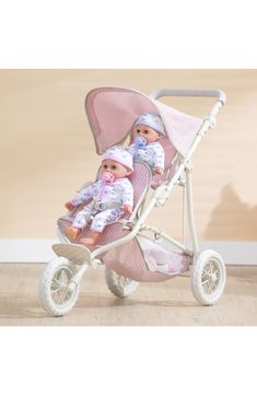 two dolls are sitting in a baby stroller