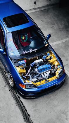 a blue car with its hood open and the engine in it's trunk is shown from above