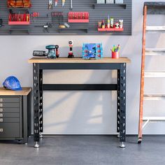 a workbench with tools on it in front of a wall mounted pegboard