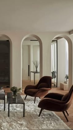 a living room filled with lots of furniture next to tall arched windows on either side of the wall