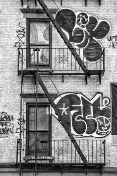 a black and white photo of graffiti on the side of a building with stairs leading up to it