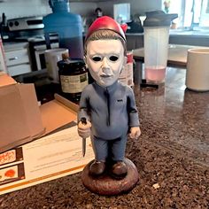 a statue of a person wearing a mask and holding a knife on top of a counter