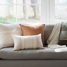 a couch with several pillows on it in front of a window