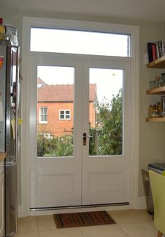 a kitchen with two doors and a rug on the floor