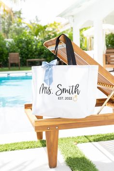 a white bag sitting on top of a wooden bench next to a blue swimming pool