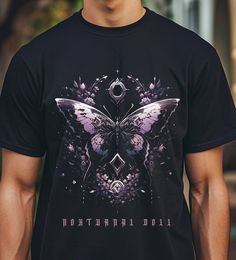 "\"Prismoth\" Tee  Step into the mysterious realm of Gothic allure with our captivating Gothic Butterfly Tee! Crafted to ignite fascination and curiosity, this shirt combines the ethereal beauty of a butterfly with the enigmatic charm of the night, resulting in a truly unique fashion piece. 🖤 Inspired Design: Our design seamlessly marries the delicate elegance of a butterfly with the haunting allure of Gothic aesthetics, creating a visual tapestry that speaks volumes about the allure of darkness. 🖤 Dark Aesthetic: Embrace your inner darkness with the striking Gothic undertones of our Butterfly Tee. Perfect for those who appreciate the beauty found within shadows, this tee is a statement of individuality and style. 🖤 Premium Quality: Made from high-quality materials, our Gothic Butterfly Mystical Short Sleeve Top With Graphic Print, Mystical Graphic Print Short Sleeve Top, Mystical Graphic Print Cotton Tops, Mystical Graphic Print Crew Neck Top, Mystical Cotton Tops With Graphic Print, Mystical Black Top With Graphic Print, Mystical Black Tops With Graphic Print, Mystical Butterfly, Gothic Butterfly