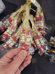 a hand is holding some candy wrapped in plastic and gold foil with pink flowers on it