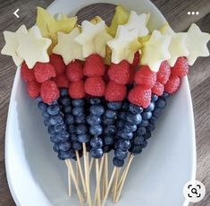 a white plate topped with red, white and blue fruit on skewered sticks