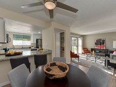 a dining room table with chairs and a basket on it in front of a kitchen