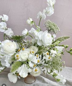 a vase filled with white flowers and greenery