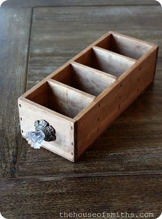 a wooden box with three compartments sitting on top of a table