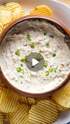 a bowl filled with white dip surrounded by chips