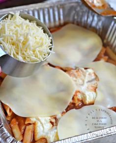 someone is pouring gravy on some ravioli in a baking pan with cheese