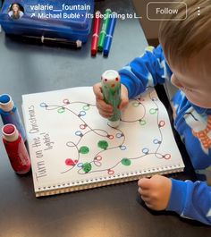 a young child is playing with a paper toy on a table next to markers and pens