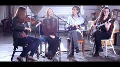 four people sitting in chairs playing guitars and singing