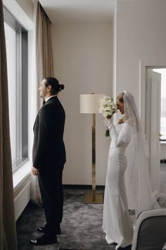 a bride and groom standing in front of a window