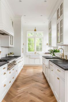 a kitchen with white cabinets and black counter tops, wood flooring in the middle