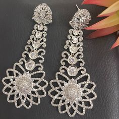 These Silver Rhinestone Sparkling Earrings drops are of a unique Elegant Floral Design of exquisite rhinestone statement and these Chandelier Earrings will draw the attention they deserve. Each silver Ballroom Earring sparkles with fine-quality cubic zirconia accented with high-quality copper, brass, and rhodium, surrounded by clusters of rhinestones in a floral design. These earrings are perfect for every occasion, from day to night.  Details: * COLOR:  Silver and Clear * MATERIAL:  High-qualit Dazzling Chandelier Earrings With Diamond Accents, Glamorous Crystal Chandelier Earrings With Elegant Design, Dazzling Chandelier Earrings With Sparkling Stones, Crystal Drop Chandelier Earrings, Party Crystal Chandelier Earrings With Elegant Design, Elegant Crystal Chandelier Earrings For Party, Diamond Chandelier Dangle Earrings For Celebration, Crystal Chandelier Earrings With Diamond Accents, Crystal Chandelier Dangle Earrings For Celebration