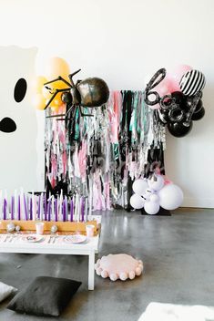 a birthday party with balloons, streamers and cake on a table in front of a white wall