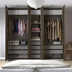 an open closet with clothes hanging on the walls and drawers, along with a bed