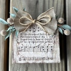 a small wooden plaque with a bow on it's head and music notes in the background