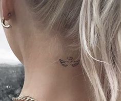 a woman with a tattoo on her neck and behind her ear is looking at the sky