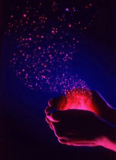 a hand holding a glowing object in the dark with pink and blue lights on it