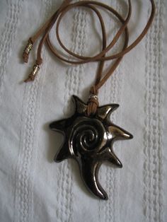 a necklace with a star and crescent design on a brown leather cord is laying on a white sheet