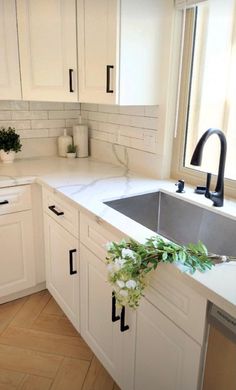 a kitchen with white cabinets and black handles on the counter top, has a sink in it