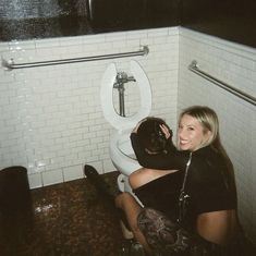 a woman sitting on the floor in front of a toilet with her arm wrapped up