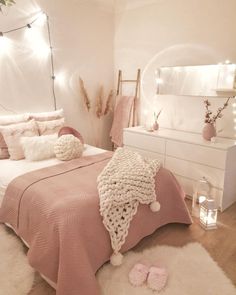 a bedroom decorated in pink and white with lights on the ceiling, bedding and rugs