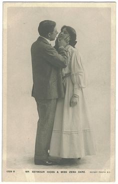 an old black and white photo of two people standing together, one kissing the other