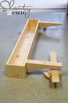 a wooden bench sitting on top of a floor next to a piece of plywood