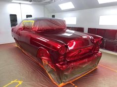 an old car is covered in plastic on the floor and ready to be put into its new paint job