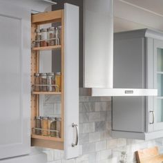 an open cabinet in the middle of a kitchen with white counter tops and gray cabinets