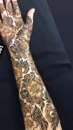 a woman's hand with henna on it and flowers painted on the arm