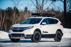 a white honda cr - v parked in the snow with skis on it's roof