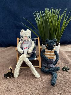 two crocheted animals sitting next to each other in front of a potted plant