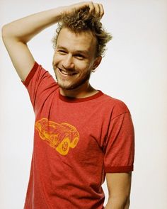 a smiling man in a red shirt is holding his hair